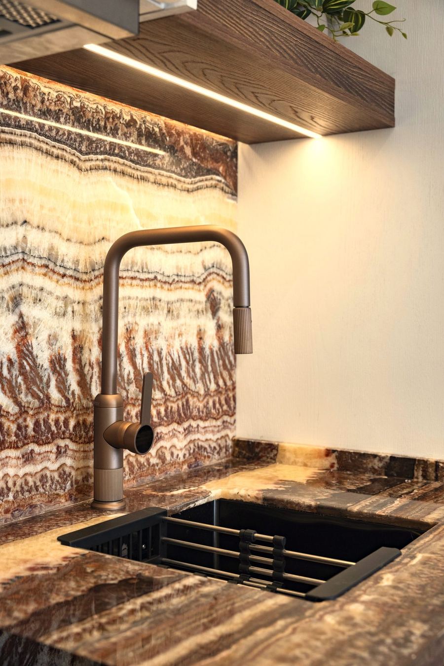 Brushed bronze faucet against bookmatched onyx backsplash