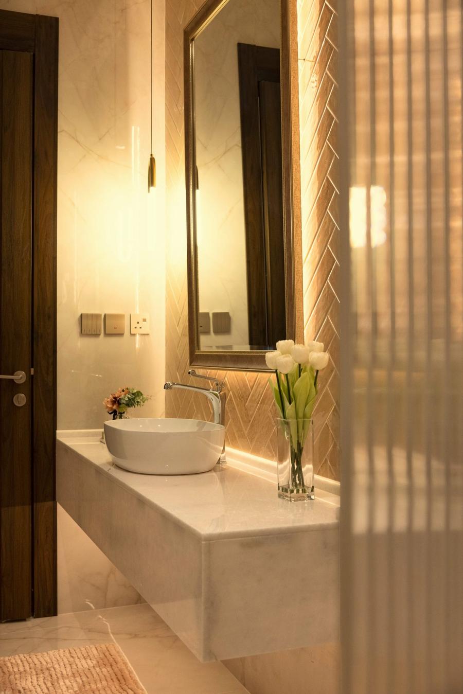 Master bathroom with herringbone gold tiles and backlit mirror